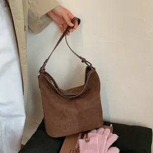 Detail einer dunkelbraunen Hobo-Tasche aus Wildleder mit verstellbarem Riemen für Damen