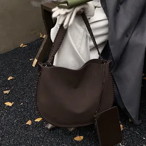 Détail du sac cabas en daim marron avec bordures tressées et mini pochette d'automne