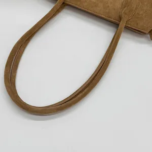 Gros plan du sac en daim caramel montrant les doubles anses et la texture mate