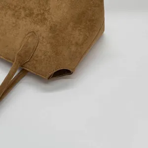 Détail macro du sac cabas en cuir givré marron montrant les coutures et la texture noble