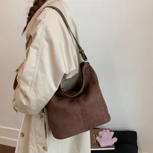 Detailansicht einer braunen Wildleder-Beuteltasche kombiniert mit einem beigen Trenchcoat