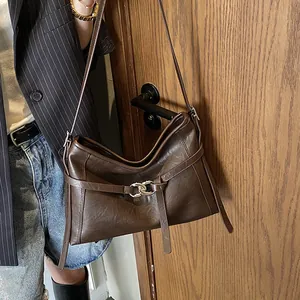 Détail d'un cabas vintage en cuir marron avec boucles métalliques et bandoulière élégante