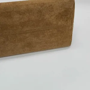Gros plan sur les coutures latérales et la texture en daim marron mat du sac