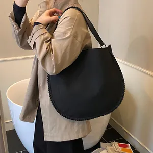 Vue détaillée du grand sac cabas noir minimaliste avec texture tressée à la main sur la bandoulière