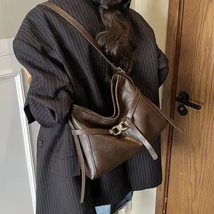 Détail du cabas en cuir marron foncé avec boucle en chaîne métallique et bandoulière souple