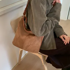 Detail einer braunen Wildleder-Beuteltasche mit Lederbesatz und verstellbarem Schultergurt