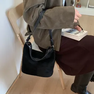 Detail einer Vintage-Eimer-Tasche aus schwarzem Wildleder mit Schultergurt am Model