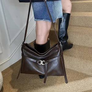 Détail d'un sac à bandoulière vintage marron foncé avec anneau métallique et fini brillant