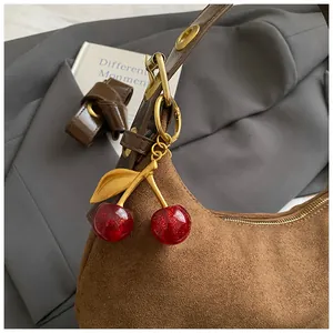 Gros plan d'une breloque cerise rouge pailletée sur un sac à bandoulière en daim