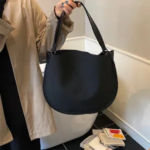 Détail du grand sac hobo noir avec des bords tressés épais et une large bandoulière tissée