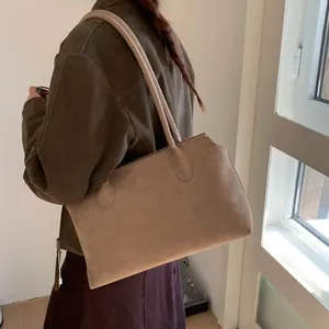 Vue latérale détaillée d'un sac cabas en daim mat kaki porté par un mannequin chic