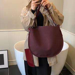 Détail d'un cabas en daim bordeaux avec surpiqûres contrastées et pochette latérale