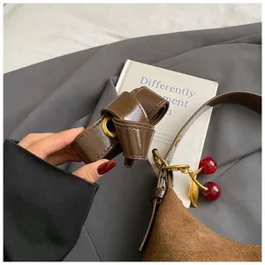 Détail du sac à bandoulière en daim marron rétro avec sangle et breloque cerise