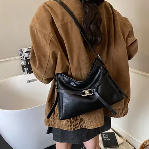 Sac hobo chic en cuir noir avec boucle nouée en argent porté par un mannequin