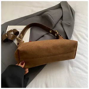 Gros plan sur le sac en daim marron avec coutures détaillées et finitions dorées