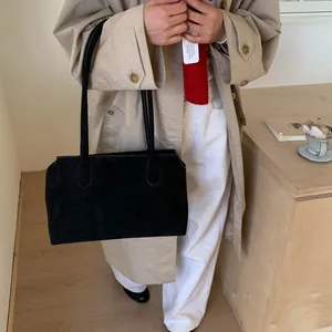Détail de la texture en daim noir mat du grand sac cabas minimaliste porté par le mannequin