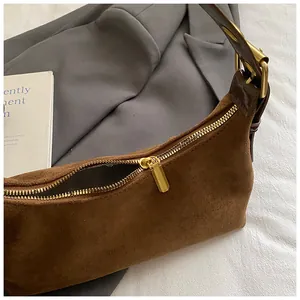 Détail du sac à main en daim marron avec fermeture éclair dorée et texture vintage