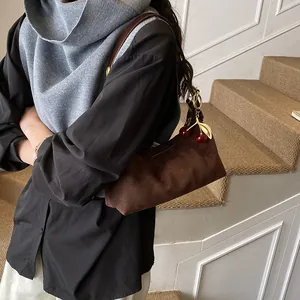 Détail du sac d'épaule en daim marron foncé mat avec un charmant pendentif cerise en métal