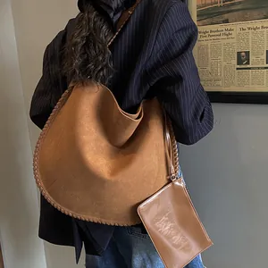 Détail d'un sac hobo en daim marron avec coutures tressées décoratives et pochette assortie