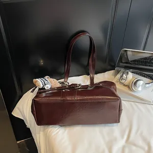 Détail du sac cabas marron foncé en similicuir brillant avec un charmant pendentif ours