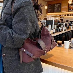 Detail der burgunderroten Wildledertasche mit Lederriemen in gemütlicher Café-Umgebung
