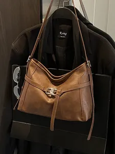 Sac à main rétro en cuir marron foncé avec boucle argentée sur fond de costume élégant
