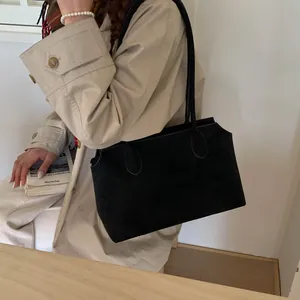 Grand sac fourre-tout noir mat porté avec un trench-coat beige pour un look chic