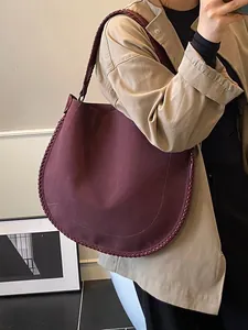 Grand sac cabas bordeaux à bords tressés porté avec un trench-coat beige élégant