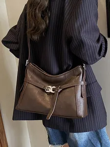 Sac cabas marron rétro avec boucle argentée porté par un mannequin en veste blazer