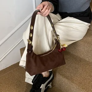 Détail du sac hobo mat marron foncé avec un charm cerise et des œillets dorés