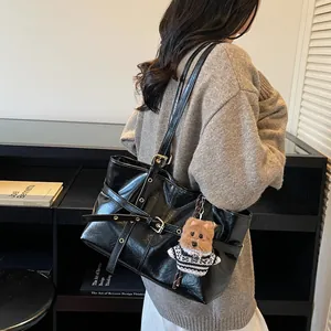 Détail d'un grand sac cabas noir en similicuir avec boucle décorative et breloque ourson