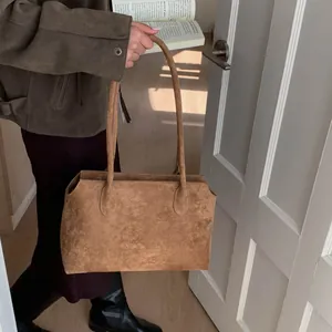 Détails d'un grand cabas en daim marron avec fines bandoulières et texture mate