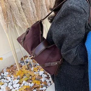 Detail der weinroten Wildleder-Schultertasche mit Lederbesatz und goldenen Metallteilen