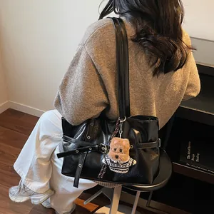 Détail d'un sac d'épaule en cuir PU noir avec un pendentif chien en peluche et une boucle