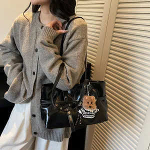 Détail du sac cabas en cuir verni noir brillant avec un joli pendentif chiot en peluche
