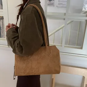 Détail du sac cabas en daim marron mat avec fines bandoulières et fermeture éclair