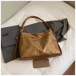 Detail of vintage bronze tote bag with distressed texture and elegant gold hardware