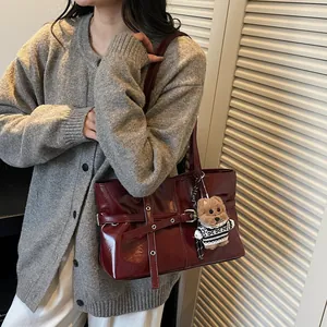 Détail du sac cabas en cuir verni bordeaux avec boucle de sangle et accessoire ours