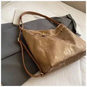 Detail of tan corduroy tote bag showing soft velvet texture and gold buckle strap