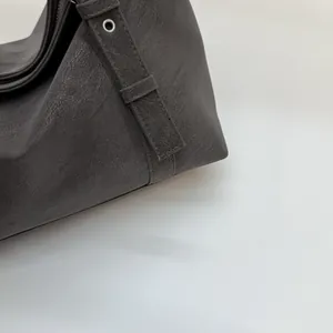 Détail de l'œillet métallique argenté et couture du sac à bandoulière en cuir gris foncé