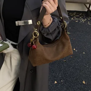 Détail du sac porté épaule en daim marron avec un pendentif cerise 3D de style vintage