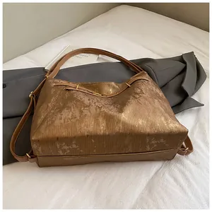 Detail of brown metallic tote bag showing vertical textures and golden metal buckle