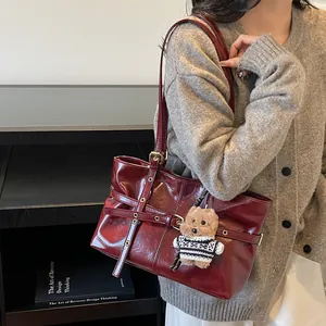 Détail du sac sous l'aisselle bordeaux brillant avec œillets et un charmant chien en peluche