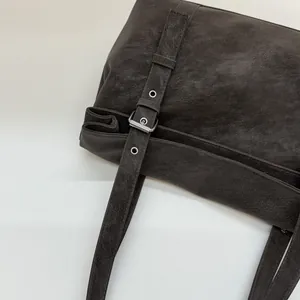 Détail de la bandoulière réglable et de la boucle en métal argenté du sac en cuir