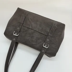 Détail du sac en cuir marron vintage montrant les bretelles réglables et ferrures argentées