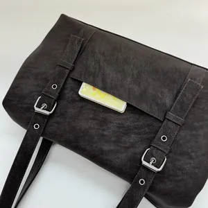 Détail du sac bandoulière marron foncé en cuir texturé avec boucles argentées élégantes