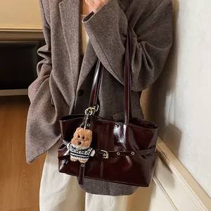 Détail d'un grand sac cabas bordeaux en cuir verni avec clous et un charmant ours en peluche