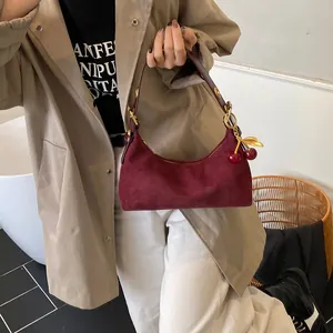Détail du sac croissant en cuir dépoli bordeaux avec un accessoire breloque cerise dorée