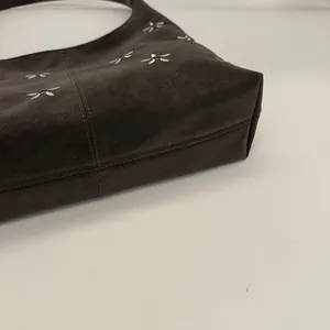 Détails de la broderie de nœud argenté et des coutures sur le sac cabas marron