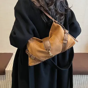 Detail einer braunen Wildleder-Schultertasche mit Metallhaken und Lederbesatz am Mantel